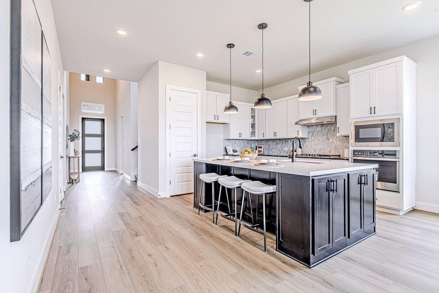 The open-concept kitchen blends style and function with an oversized island, designer pendant lights, and seamless flow to the main living spaces.