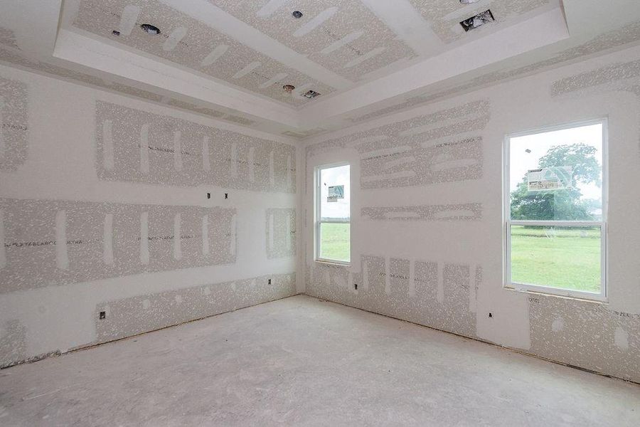 Spacious primary bedroom under construction, featuring large windows that invite natural light and offer scenic views of the lush outdoors. Spacious primary bedroom under construction, featuring large windows that invite natural light and offer scenic views of the lush outdoors.