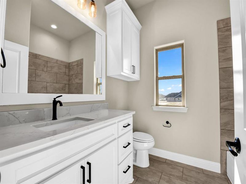 Bathroom with toilet, vanity, and tile patterned floors