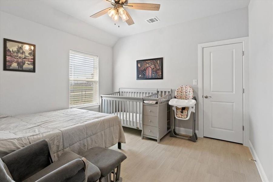 Bedroom with baseboards, vaulted ceiling, visible vents, and light wood-style floors