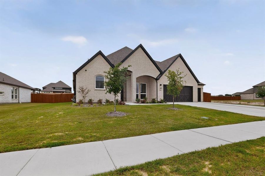 Contemporary brick residence featuring a prominent gabled roofline, an integrated two-car garage, established front landscaping, and a concrete driveway Contemporary brick residence featuring a prominent gabled roofline, an integrated two-car garage, established front landscaping, and a concrete driveway