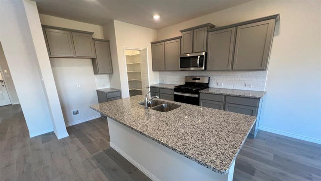 Kitchen with gray cabinets, tasteful backsplash, light stone countertops, appliances with stainless steel finishes, and recessed lighting