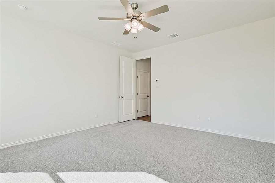 Carpeted empty room featuring ceiling fan