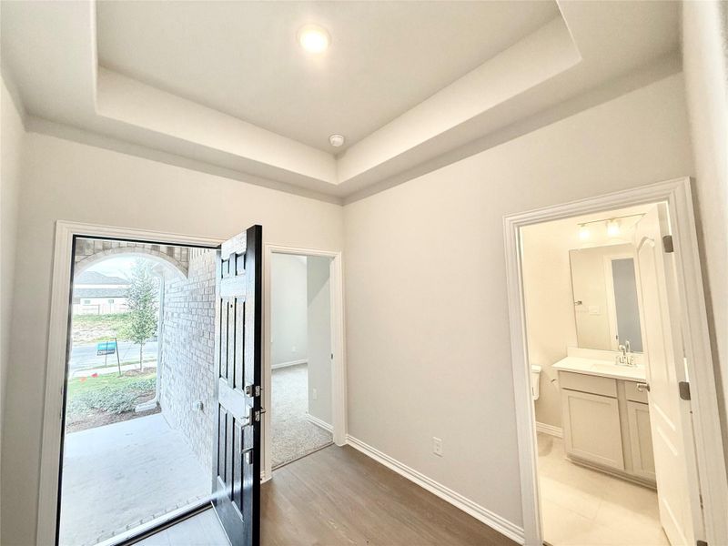 Foyer entrance featuring a tray ceiling and light wood-type flooring Foyer entrance featuring a tray ceiling and light wood-type flooring