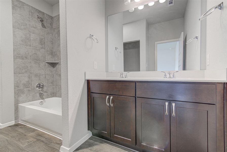 Modern bath offering dual vanities and a tiled shower-tub combination. Modern bath offering dual vanities and a tiled shower-tub combination.