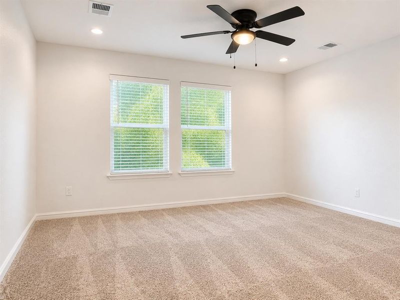 Carpeted room featuring two windows with horizontal blinds, a ceiling fan with integrated lighting, and recessed ceiling lights