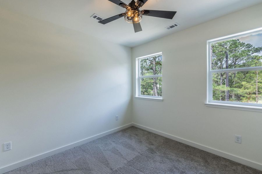 Room featuring two windows, neutral wall tones, gray carpet, white baseboards, and a ceiling fan with light fixture Room featuring two windows, neutral wall tones, gray carpet, white baseboards, and a ceiling fan with light fixture