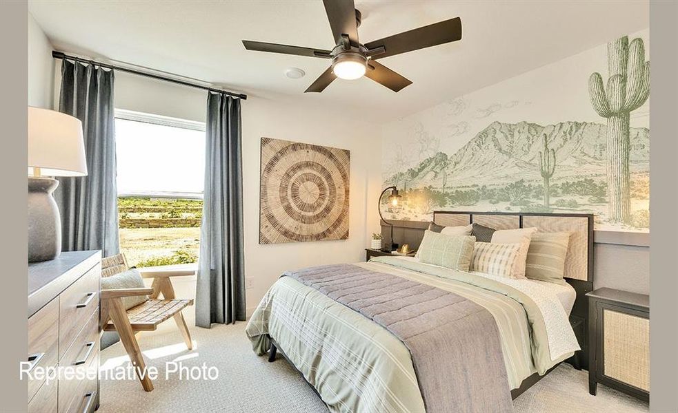Carpeted bedroom featuring a large window, ceiling fan with integrated lighting, and a decorative wall mural