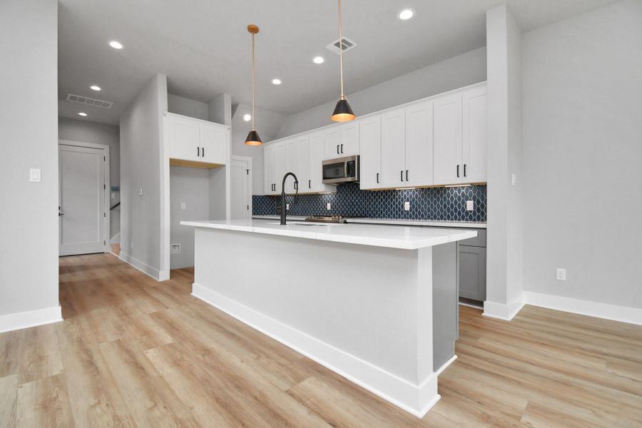 Modern kitchen with a spacious island, sleek finishes, and designer backsplash. Open layout with abundant natural light, perfect for entertaining.