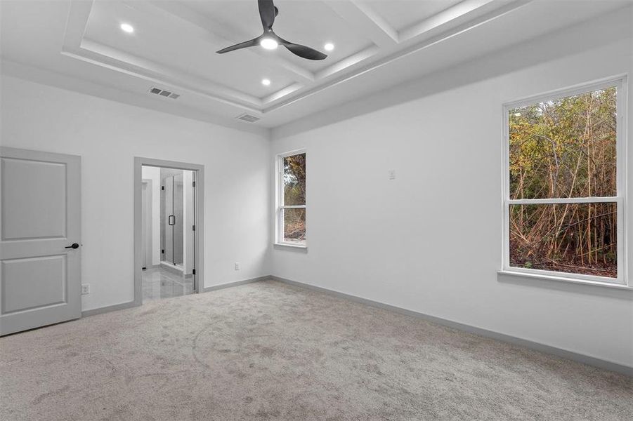 Carpeted empty room featuring ceiling fan, a healthy amount of sunlight, beam ceiling, and coffered ceiling