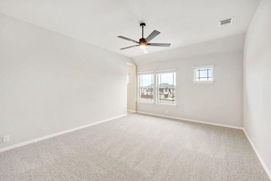 Empty bedroom with carpet flooring, ceiling fan with light, and two windows with neighborhood view