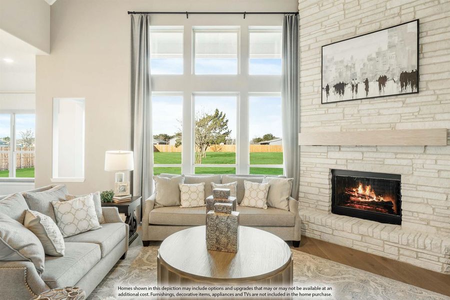 Living room with two-story windows, stone fireplace, and neutral sofas on hardwood floors
