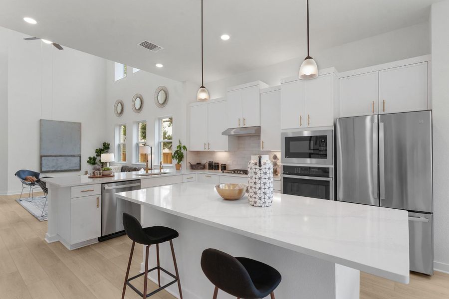 Kitchen featuring stainless steel appliances, under cabinet range hood, a peninsula, a sink, and tasteful backsplash