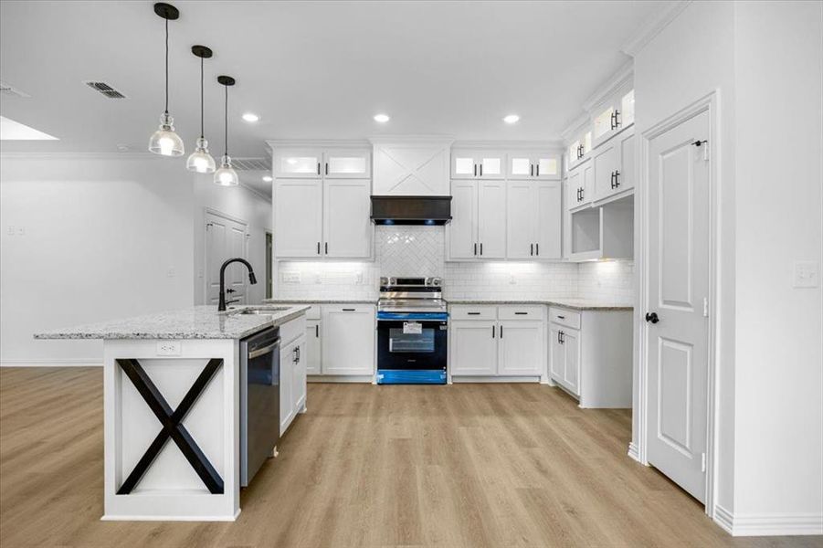 Kitchen featuring stainless steel appliances, white cabinets, glass insert cabinets, decorative light fixtures, and light stone counters