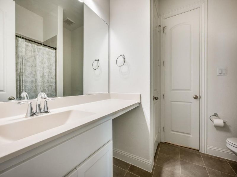 Full bathroom featuring tile patterned flooring, vanity, toilet, baseboards, and visible vents
