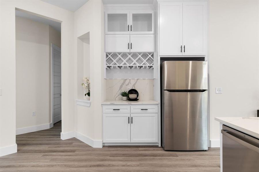 Kitchen featuring light hardwood / wood-style flooring, stainless steel appliances, white cabinetry, and light stone counters