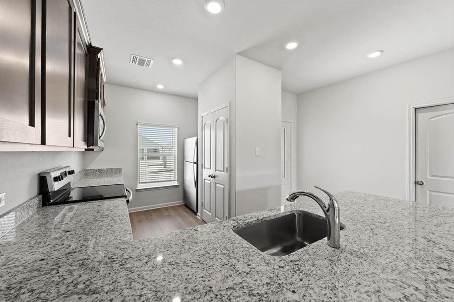 Kitchen with light stone countertops, stainless steel appliances, light wood-style flooring, and recessed lighting Kitchen with light stone countertops, stainless steel appliances, light wood-style flooring, and recessed lighting