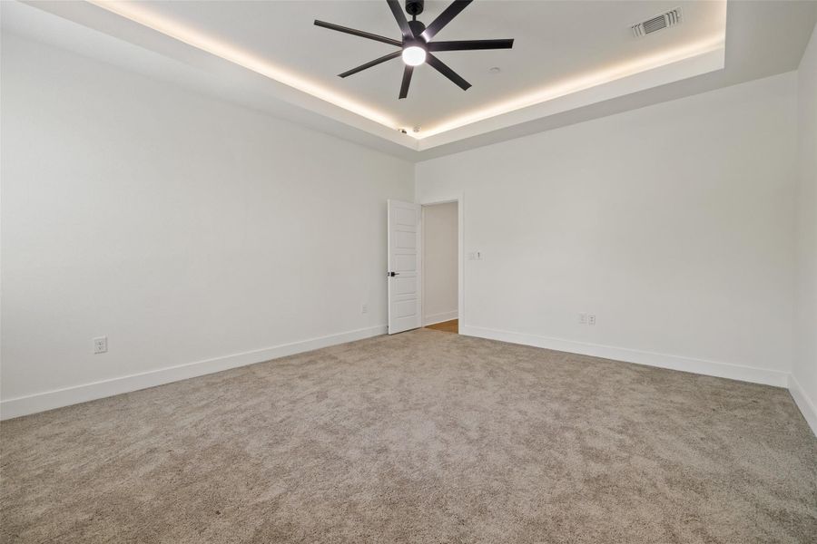Unfurnished room featuring a raised ceiling, carpet floors, and ceiling fan Unfurnished room featuring a raised ceiling, carpet floors, and ceiling fan