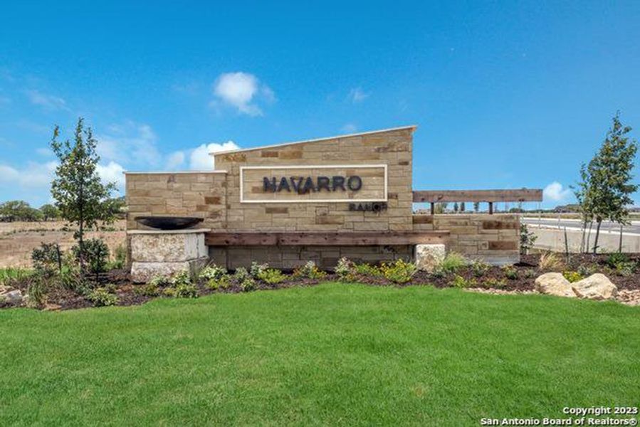 Community sign featuring a lawn Community sign featuring a lawn