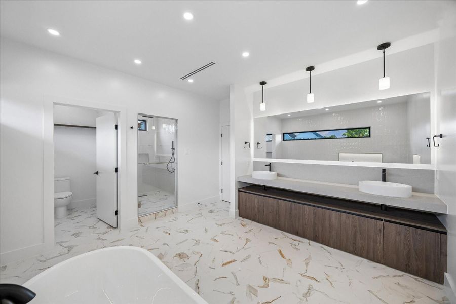 Double vanity with elegant pendant lighting, a walk-in shower, and a separate toilet area, all set on beautiful marble flooring. Double vanity with elegant pendant lighting, a walk-in shower, and a separate toilet area, all set on beautiful marble flooring.
