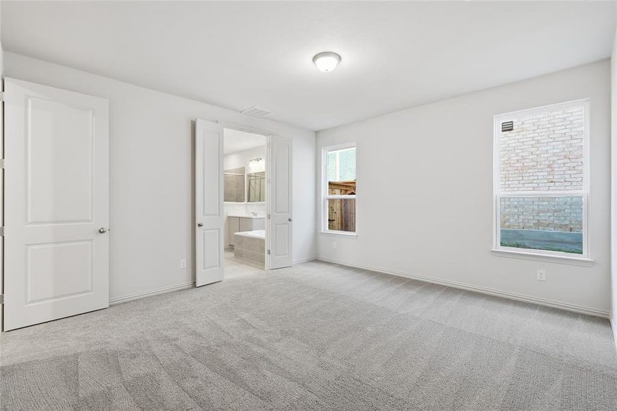 Unfurnished bedroom with connected bathroom and carpet flooring