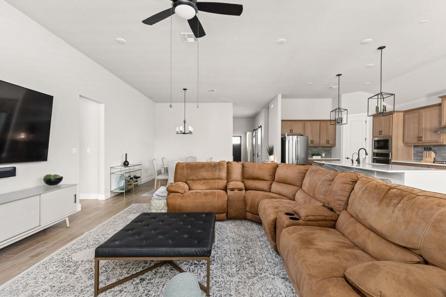 Living room with suspended lighting, light wood-type flooring, and ceiling fan
