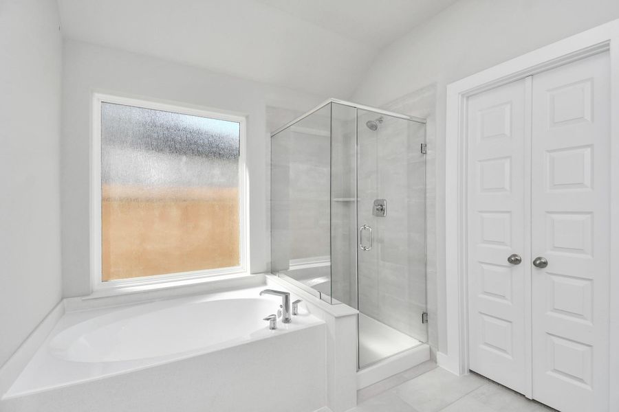 Indulge in a spa-like retreat within the confines of this primary bathroom. Delight in a spacious walk-in shower enveloped in stylish tile surround and unwind in a separate garden tub adorned with custom detailing. Sample photo of completed home with similar floor plan. Actual colors and selections may vary. Indulge in a spa-like retreat within the confines of this primary bathroom. Delight in a spacious walk-in shower enveloped in stylish tile surround and unwind in a separate garden tub adorned with custom detailing. Sample photo of completed home with similar floor plan. Actual colors and selections may vary.