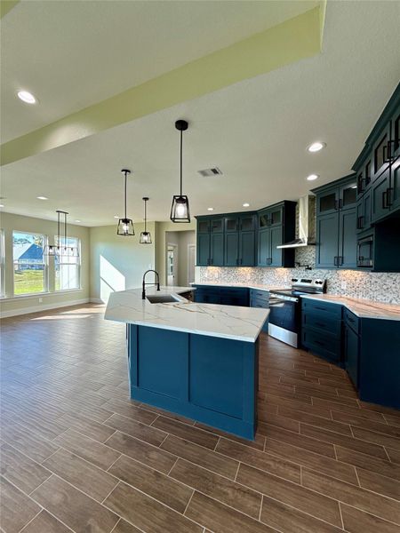 This modern kitchen features sleek dark cabinetry with a stylish Quartz countertop island. It has contemporary pendant lighting, wood-look tile flooring, and ample natural light from large windows, creating an inviting and functional space. This modern kitchen features sleek dark cabinetry with a stylish Quartz countertop island. It has contemporary pendant lighting, wood-look tile flooring, and ample natural light from large windows, creating an inviting and functional space.