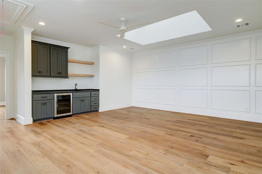 Game room up with skylight, custom accent wall, & wet bar!