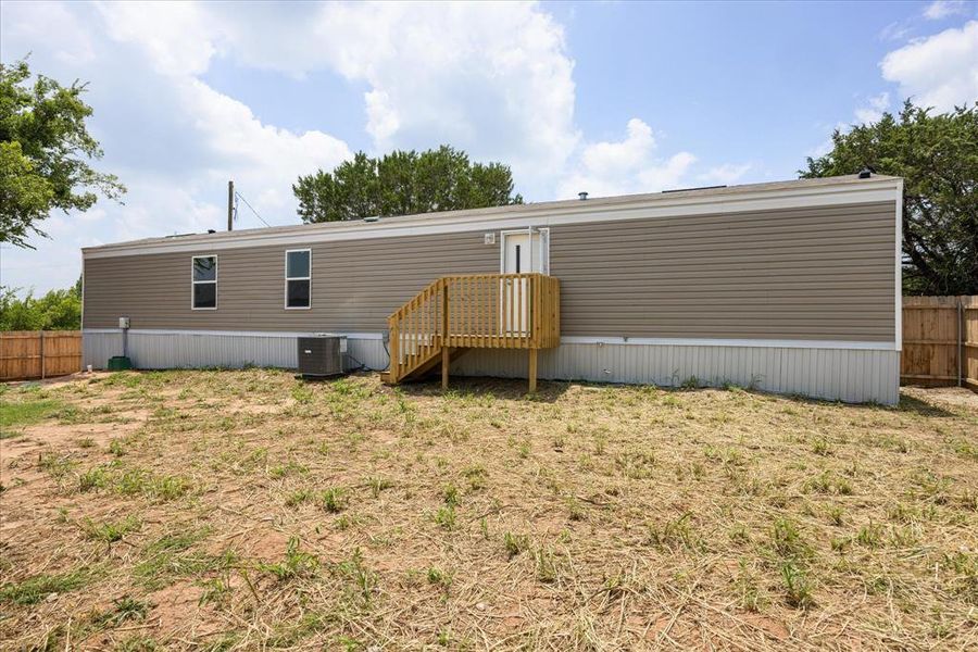 Exterior featuring horizontal vinyl siding, white trim, and a wood deck with stairs