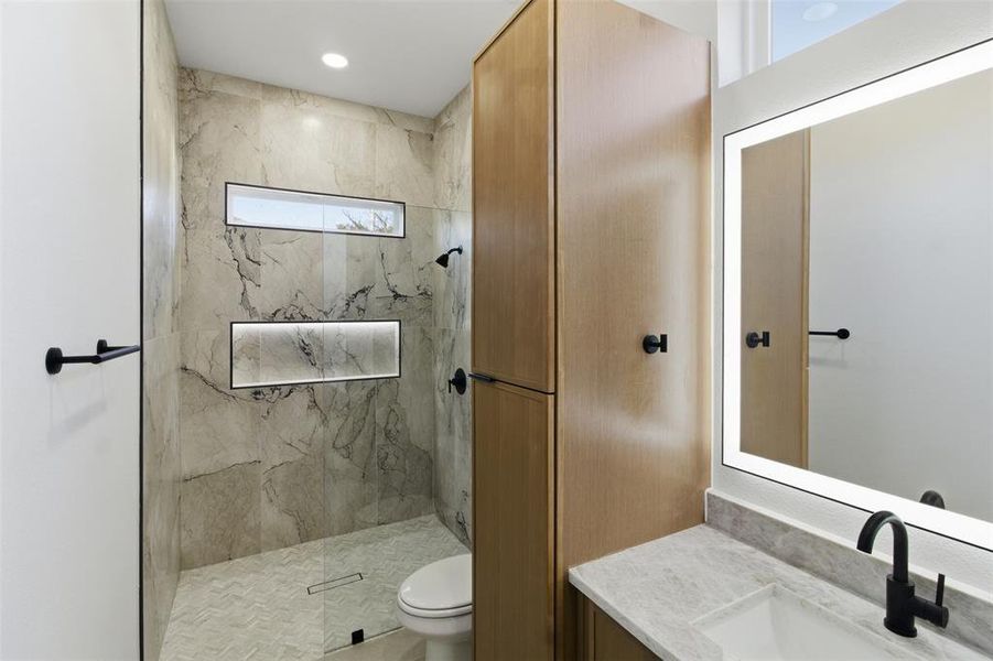 Bathroom with a marble finish shower and vanity