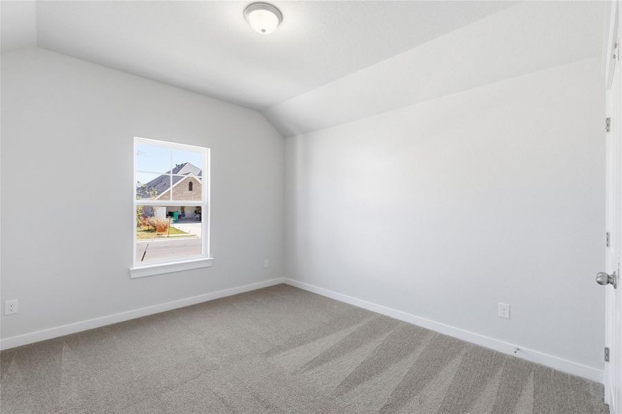 Carpeted spare room with baseboards and vaulted ceiling