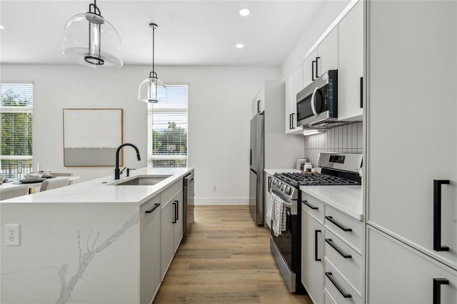 Matte finish hardware and pulls provide a true accent piece to the kitchen alongside warm light gray colored cabinetry.