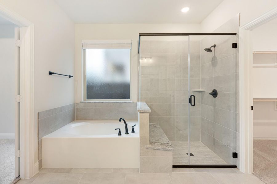 Master bathroom with soaking tub, glass-enclosed tile shower, and dark bronze fixtures on white walls Master bathroom with soaking tub, glass-enclosed tile shower, and dark bronze fixtures on white walls