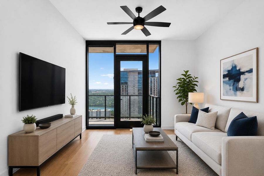 Cityscape views from this living room with a door leading to the balcony and wood flooring.