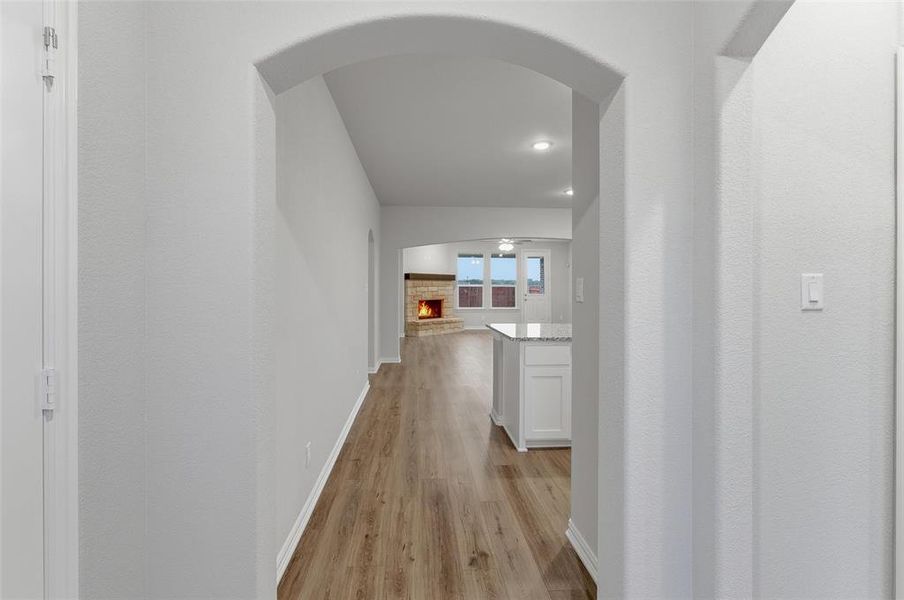 Archway entry opening to an expansive interior with wood-finish flooring Archway entry opening to an expansive interior with wood-finish flooring