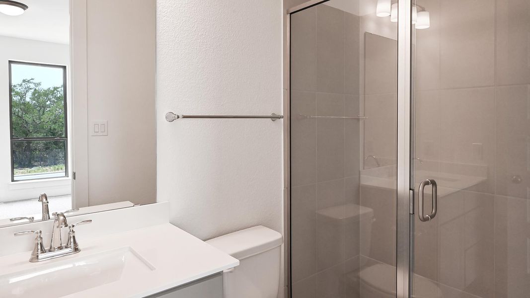 Bathroom featuring toilet, vanity, and a stall shower Bathroom featuring toilet, vanity, and a stall shower