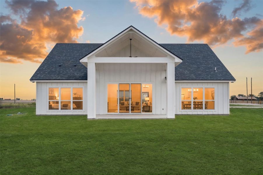 Board and batten siding meets a covered patio against a grassy backyard space.