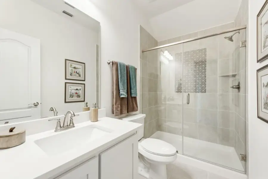 Bathroom with white vanity, glass-enclosed tile shower, and toilet in neutral tones