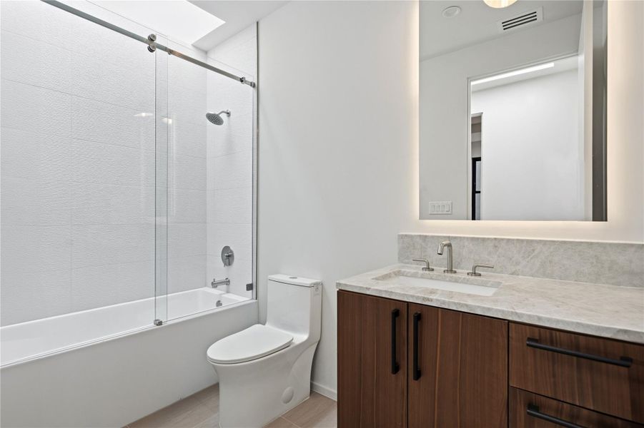 A well-appointed bath features modern fixtures and a glass-enclosed shower over the tub.