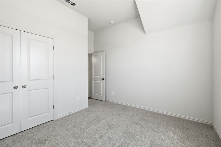 Unfurnished bedroom featuring light colored carpet and a closet
