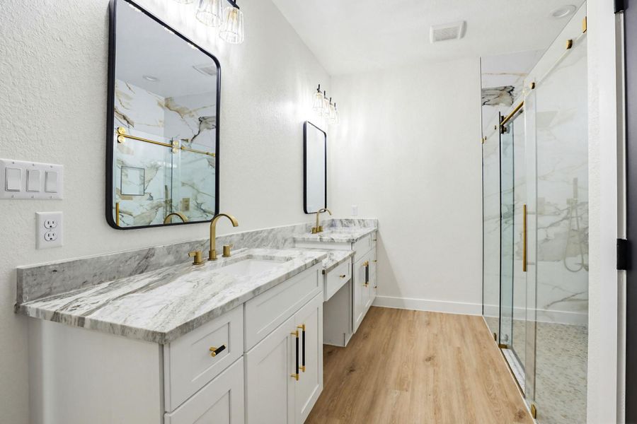 Marble-veined countertops and a spacious glass-enclosed shower elevate this contemporary primary bathroom.