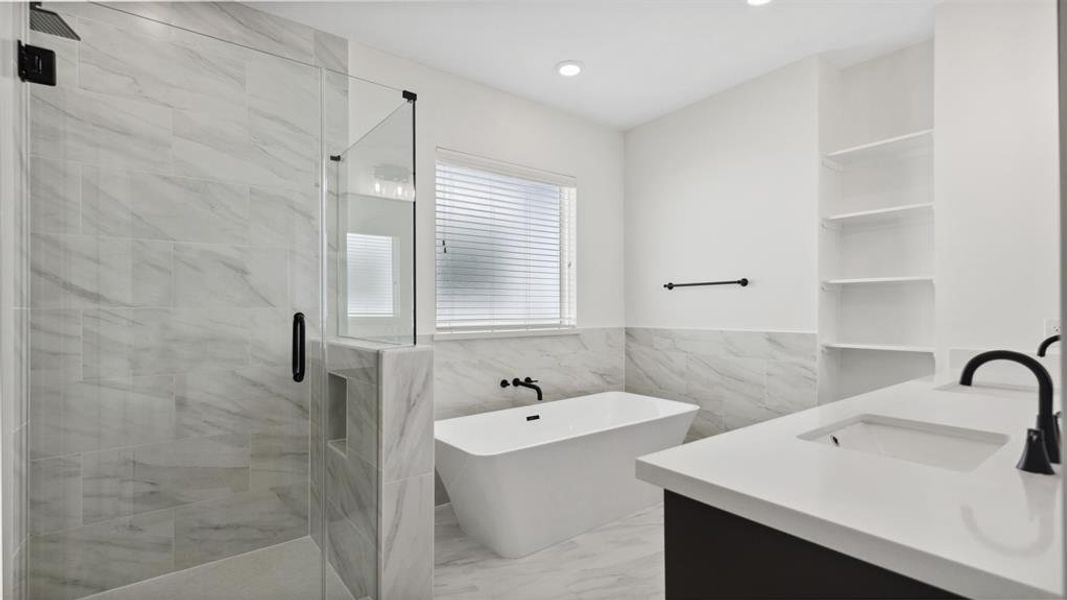 This modern bathroom features a sleek glass-enclosed shower, a freestanding bathtub, and a stylish vanity with a contemporary faucet. The space is accented with elegant marble tiles and built-in shelving, offering a bright and luxurious atmosphere.