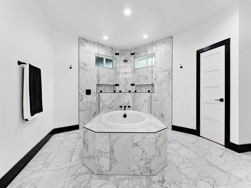 Luxurious bathroom featuring a built-in soaking tub, marble-style tile flooring, and a spacious walk-in shower with dual shower heads