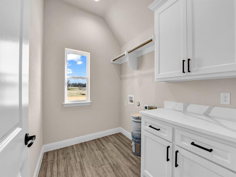 Laundry room with washer hookup, cabinets, and light wood-type flooring