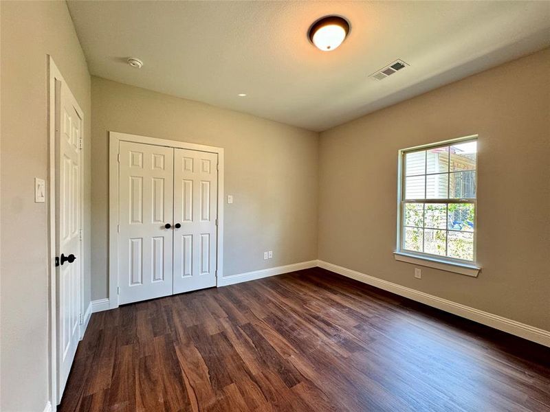 Unfurnished bedroom featuring dark hardwood / wood-style flooring and a closet