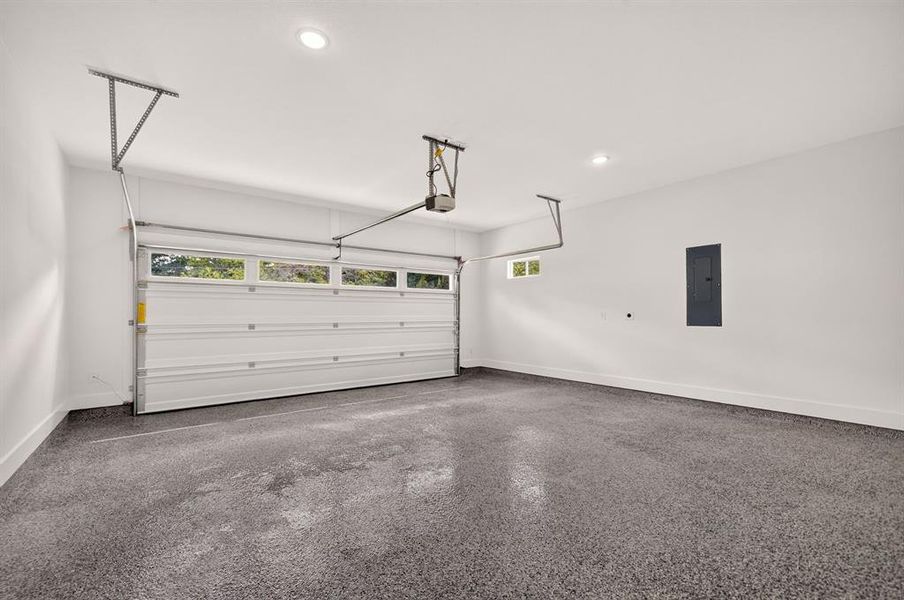 Two-car garage featuring a speckle-finish epoxy floor, overhead lighting, and a garage door with transom-style windows