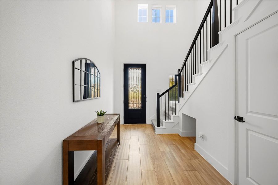 An 8-foot entry door welcomes you inside, where the stairway to the second floor adds an elegant architectural touch with wrought iron spindles and a decorative chandelier that brings warmth and character to the space. An 8-foot entry door welcomes you inside, where the stairway to the second floor adds an elegant architectural touch with wrought iron spindles and a decorative chandelier that brings warmth and character to the space.