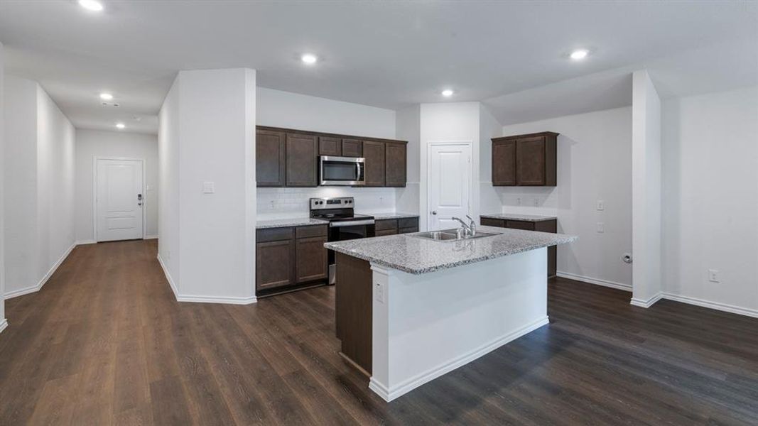 Kitchen with dark wood finish cabinets, stainless steel appliances, an island with sink, dark wood finished floors, and recessed lighting