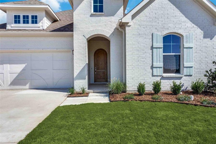View of front of property featuring concrete driveway, brick siding, a front lawn, and a garage View of front of property featuring concrete driveway, brick siding, a front lawn, and a garage
